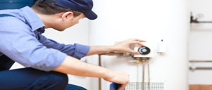 A technician looking into a hot water unit