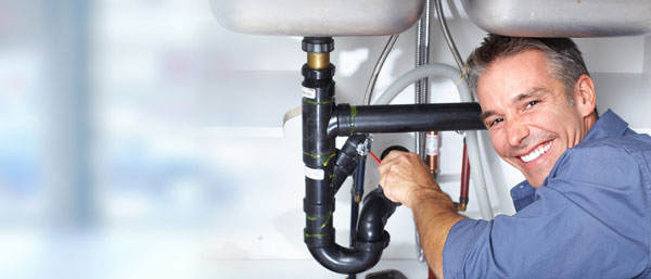 A friendly plumber at work in a kitchen.